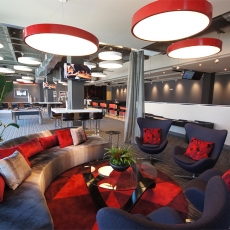 Recreation  area with a grey couch, black loveseats, and red hanging lighting fixtures