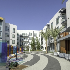 Entrance to leasing center of apartment complex with multi colored panels on the left and two palm trees on the right