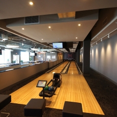 Two lane bowling alley with lights hanging on a track